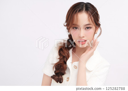 A beautiful young Asian woman with clean, fresh skin against a white background. Skincare, facial treatment, cosmetology, beauty, and spa. An elegant portrait of an Asian woman. 125282788
