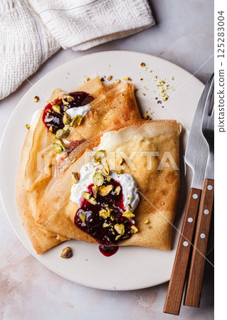 Breakfast crepes with sour cream, jam and pistachio. Breakfast crepes with sour cream, jam and pistachio. 125283004