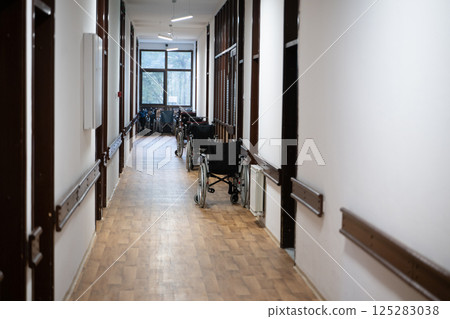 A row of wheelchairs neatly lined up in a hospital corridor, ready for patients in need of mobility assistance A row of wheelchairs neatly lined up in a hospital corridor, ready for patients in need of mobility assistance 125283038
