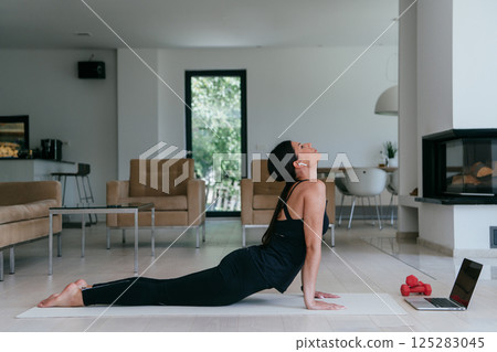 Young Beautiful Female Exercising, Stretching and Practising Yoga with Trainer via Video Call Conference in Bright Sunny House. Healthy Lifestyle, Wellbeing and Mindfulness Concept 125283045