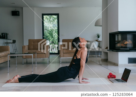 Young Beautiful Female Exercising, Stretching and Practising Yoga with Trainer via Video Call Conference in Bright Sunny House. Healthy Lifestyle, Wellbeing and Mindfulness Concept 125283064