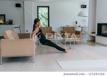 Young Beautiful Female Exercising, Stretching and Practising Yoga with Trainer via Video Call Conference in Bright Sunny House. Healthy Lifestyle, Wellbeing and Mindfulness Concept 125283160