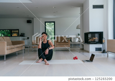 Woman Relaxing After Home Workout in a Modern Living Room Woman Relaxing After Home Workout in a Modern Living Room 125283200