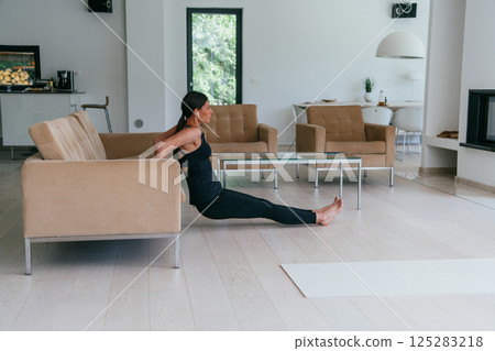 Young Beautiful Female Exercising, Stretching and Practising Yoga with Trainer via Video Call Conference in Bright Sunny House. Healthy Lifestyle, Wellbeing and Mindfulness Concept Young Beautiful Female Exercising, Stretching and Practising Yoga with Trainer via Video Call Conference in Bright Sunny House. Healthy Lifestyle, Wellbeing and Mindfulness Concept 125283218