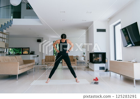 Young Beautiful Female Exercising, Stretching and Practising Yoga with Trainer via Video Call Conference in Bright Sunny House. Healthy Lifestyle, Wellbeing and Mindfulness Concept 125283291