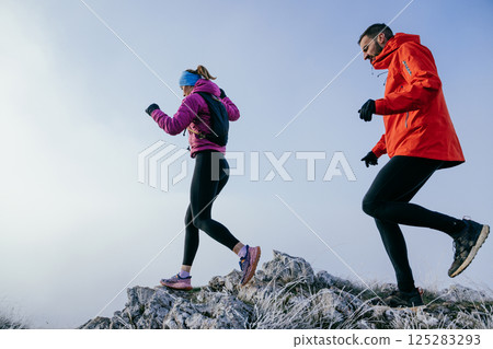 Trail running couple man and woman running on a mountain path 125283293
