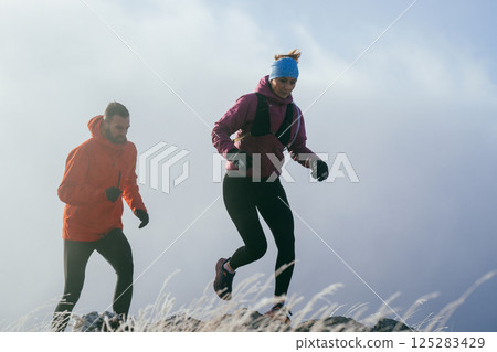 Trail running couple man and woman running on a mountain path 125283429