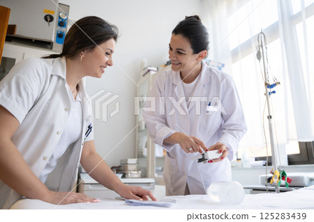 Two nurses in a hospital laboratory are carefully inspecting and preparing medications for patients and hospital use. 125283439