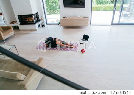 Young Beautiful Female Exercising, Stretching and Practising Yoga with Trainer via Video Call Conference in Bright Sunny House. Healthy Lifestyle, Wellbeing and Mindfulness Concept 125283544