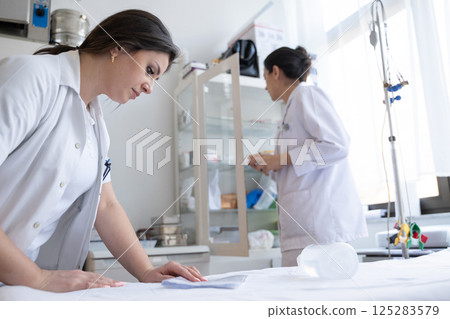 Two nurses in a hospital laboratory are carefully inspecting and preparing medications for patients and hospital use. 125283579
