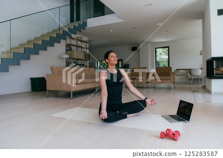 Young Beautiful Female Exercising, Stretching and Practising Yoga with Trainer via Video Call Conference in Bright Sunny House. Healthy Lifestyle, Wellbeing and Mindfulness Concept. 125283587