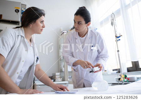 Two nurses in a hospital laboratory are carefully inspecting and preparing medications for patients and hospital use. 125283626
