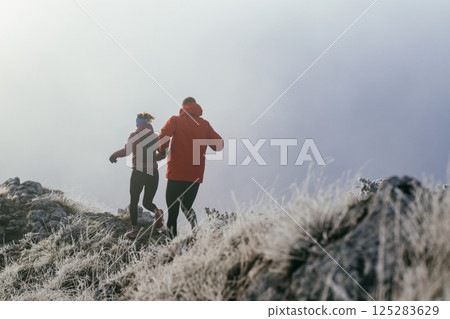 Trail running couple man and woman running on a mountain path 125283629