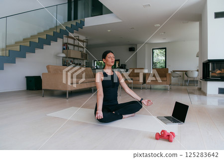 Young Beautiful Female Exercising, Stretching and Practising Yoga with Trainer via Video Call Conference in Bright Sunny House. Healthy Lifestyle, Wellbeing and Mindfulness Concept. 125283642