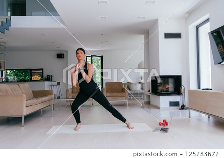 Young Beautiful Female Exercising, Stretching and Practising Yoga with Trainer via Video Call Conference in Bright Sunny House. Healthy Lifestyle, Wellbeing and Mindfulness Concept 125283672