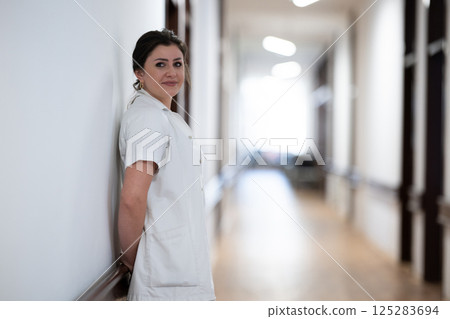 A tired nurse takes a quiet moment to rest in the hospital hallway, reflecting on a long and demanding shift. A tired nurse takes a quiet moment to rest in the hospital hallway, reflecting on a long and demanding shift. 125283694