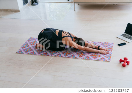 Young Beautiful Female Exercising, Stretching and Practising Yoga with Trainer via Video Call Conference in Bright Sunny House. Healthy Lifestyle, Wellbeing and Mindfulness Concept 125283737