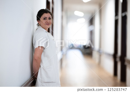 A tired nurse takes a quiet moment to rest in the hospital hallway, reflecting on a long and demanding shift. A tired nurse takes a quiet moment to rest in the hospital hallway, reflecting on a long and demanding shift. 125283747