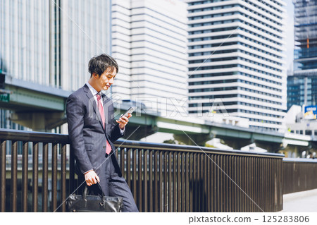 A man using a smartphone in an office district A man using a smartphone in an office district 125283806