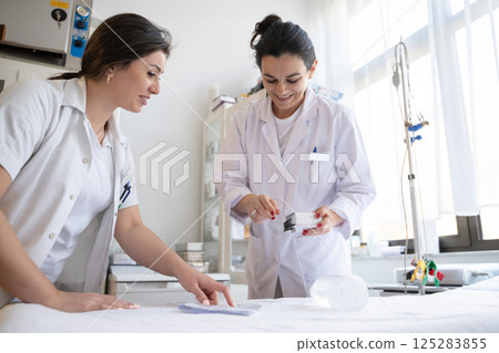Two nurses in a hospital laboratory are carefully inspecting and preparing medications for patients and hospital use. 125283855