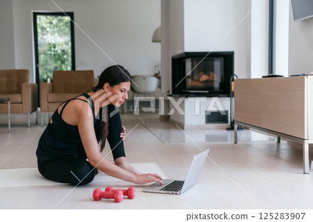 Young Beautiful Female Exercising, Stretching and Practising Yoga with Trainer via Video Call Conference in Bright Sunny House. Healthy Lifestyle, Wellbeing and Mindfulness Concept. 125283907