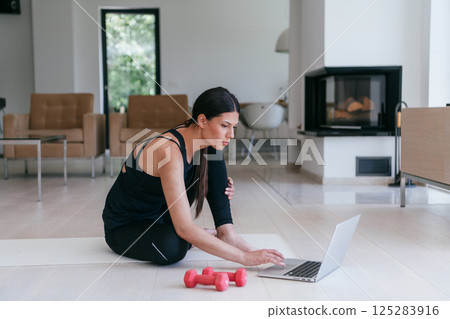 Young Beautiful Female Exercising, Stretching and Practising Yoga with Trainer via Video Call Conference in Bright Sunny House. Healthy Lifestyle, Wellbeing and Mindfulness Concept. 125283916