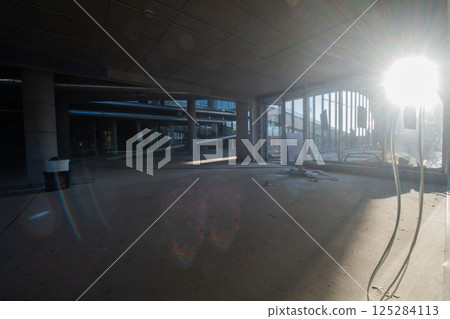 A captivating view of a modern business building under construction, showcasing its raw industrial interior with exposed steel beams and concrete walls bathed in the warm, golden hues of a sunset 125284113