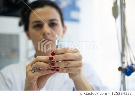 A focused nurse in a white lab coat carefully prepares a syringe for an injection in a professional healthcare environment. A focused nurse in a white lab coat carefully prepares a syringe for an injection in a professional healthcare environment. 125284152