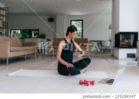Young Beautiful Female Exercising, Stretching and Practising Yoga with Trainer via Video Call Conference in Bright Sunny House. Healthy Lifestyle, Wellbeing and Mindfulness Concept. 125284347