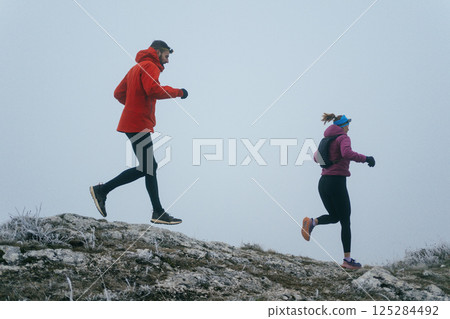 Trail running couple man and woman running on a mountain path Trail running couple man and woman running on a mountain path 125284492