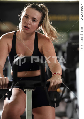 A focused fitness woman performing a conditioning workout in the gym, pushing her limits with strength, determination, and intense dedication. A focused fitness woman performing a conditioning workout in the gym, pushing her limits with strength, determination, and intense dedication. 125284507