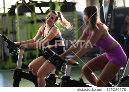 Two fitness women working together on a conditioning workout in the gym, supporting each other with strength, focus, and determination. 125284578