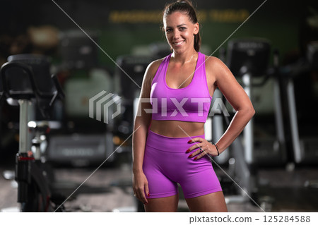 A fit woman strikes a confident pose in the gym after an intense workout, showcasing her strength, dedication, and progress. A fit woman strikes a confident pose in the gym after an intense workout, showcasing her strength, dedication, and progress. 125284588