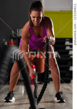 Fit Woman Performing Rope Conditioning Exercise in the Gym 125284611