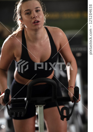 A focused fitness woman performing a conditioning workout in the gym, pushing her limits with strength, determination, and intense dedication. A focused fitness woman performing a conditioning workout in the gym, pushing her limits with strength, determination, and intense dedication. 125284638