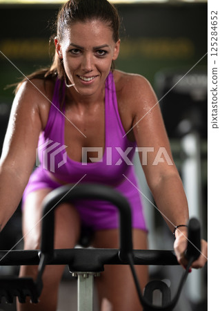 A focused fitness woman performing a conditioning workout in the gym, pushing her limits with strength, determination, and intense dedication. 125284652