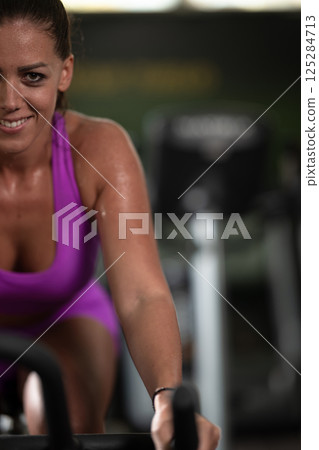 A focused fitness woman performing a conditioning workout in the gym, pushing her limits with strength, determination, and intense dedication. A focused fitness woman performing a conditioning workout in the gym, pushing her limits with strength, determination, and intense dedication. 125284713