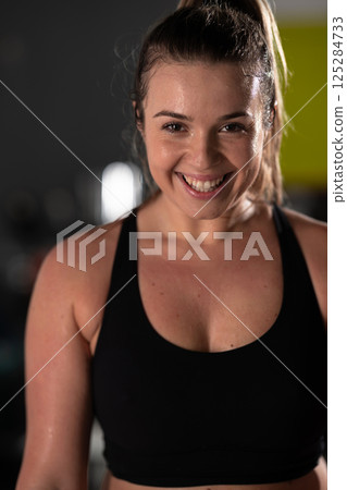 A beautiful and fit woman sitting on a gym ball with a towel, resting and recovering after an intense workout. 125284733