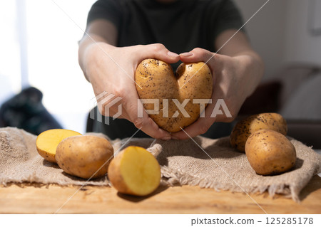 A HeartShaped Potato is Gently Embraced by Loving Hands in a Cozy Kitchen Setting 125285178