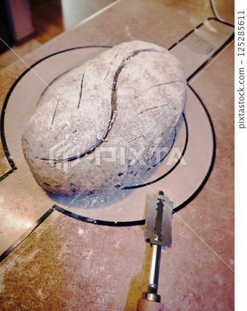 unbaked artisanal sourdough bread freshly scored with a razor before baking on silicone mat 125285611