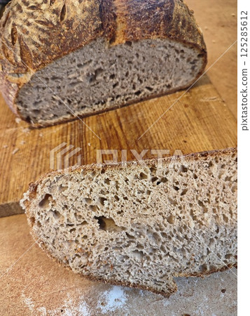 freshly cut artisanal sourdough bread showing crumb and texture on a rustic wooden surface 125285612