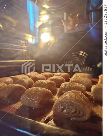 unbaked sourdough cinnamon rolls baking on a baking sheet in the oven with a swirl of cinnamon filling in oven light unbaked sourdough cinnamon rolls baking on a baking sheet in the oven with a swirl of cinnamon filling in oven light 125285617