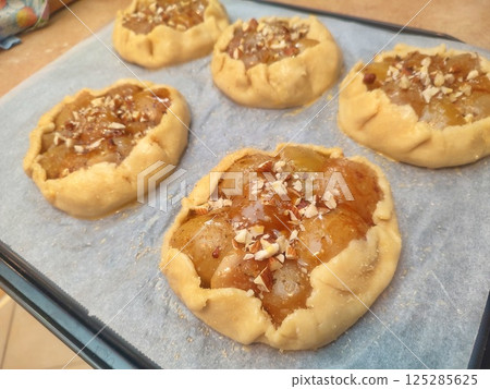 unbaked rustic apple galette with mascarpone and almonds arranged on baking paper before going into the oven 125285625