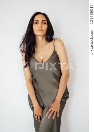 A young pregnant woman standing and gently holds her belly. White background. 125286015