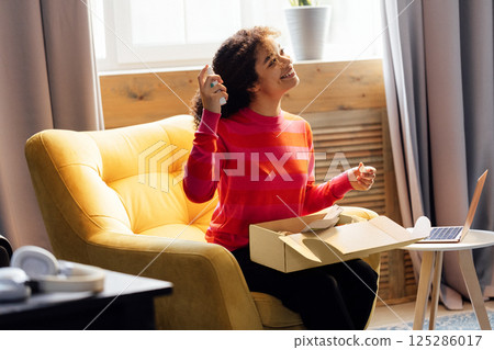 A young African woman unpacks a cardboard box with beauty products A young African woman unpacks a cardboard box with beauty products 125286017