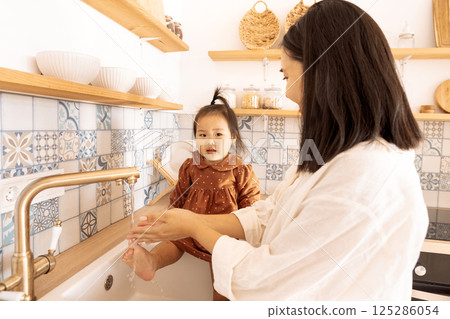 charming Korean woman and her little daughter wash their hands in the sink 125286054