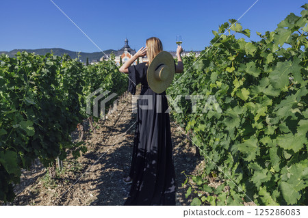 Young female walks through the vineyard. View from the back 125286083