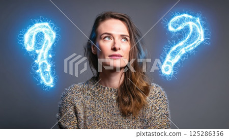 A woman stands in a studio with a neutral background. She appears thoughtful, with glowing question marks appearing on either side, conveying curiosity and introspection. A woman stands in a studio with a neutral background. She appears thoughtful, with glowing question marks appearing on either side, conveying curiosity and introspection. 125286356