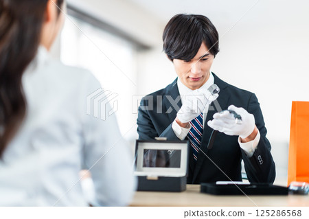 一位專業買家正在評估二手商品，一位家庭主婦正在把不需要的物品帶到商店 125286568