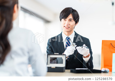 一位專業買家正在評估二手商品，一位家庭主婦正在把不需要的物品帶到商店 125286570